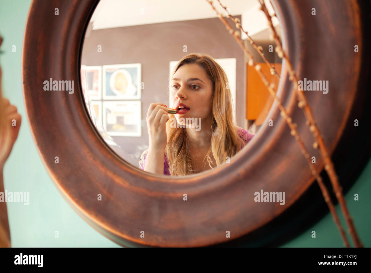 Frau Anwendung Lippenstift während im Spiegel zu Hause suchen Stockfoto