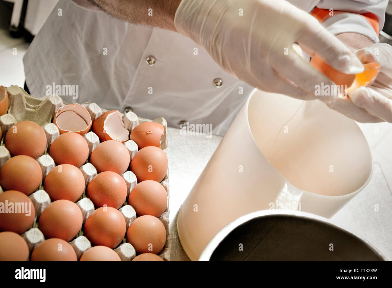 Mittelteil der Koch Eier im Glas an den Küchentisch brechen Stockfoto
