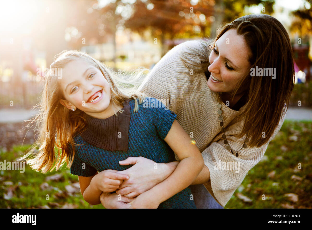 Fröhliche Mutter spielt mit Tochter im Park im Herbst Stockfoto