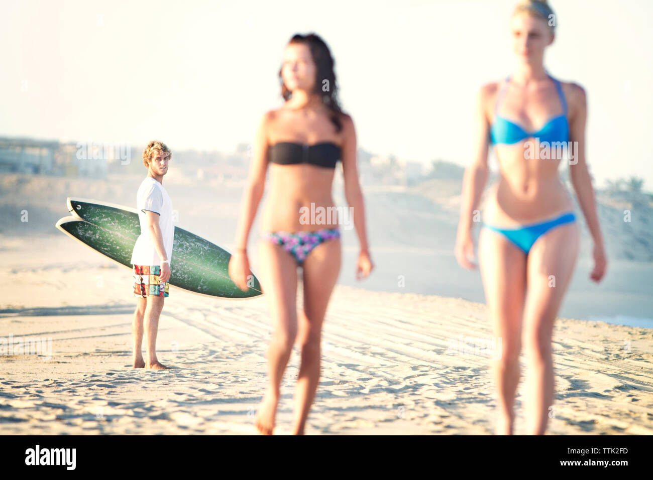 Mann an die Frauen, die im Bikini auf Sand am Strand Stockfoto