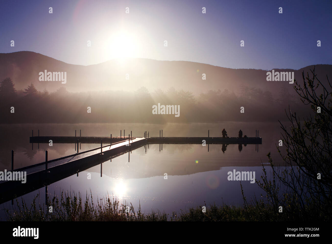 Malerischer Blick auf Pier über den See gegen Berge bei Sonnenaufgang Stockfoto