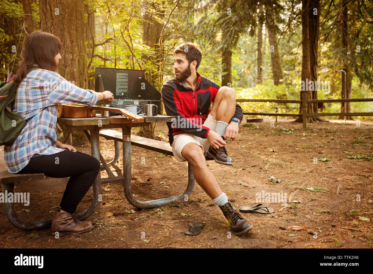 Freunde sprechen, beim Sitzen am Tisch für Picknick im Wald Stockfoto