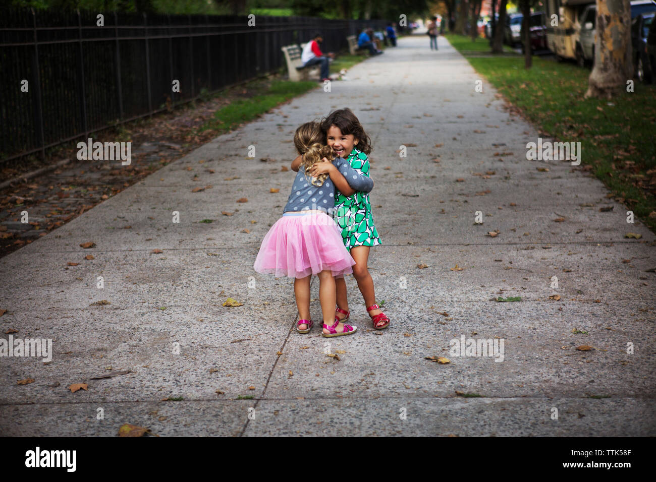 Freundliche Schwestern umarmen auf Fußweg im Park Stockfoto