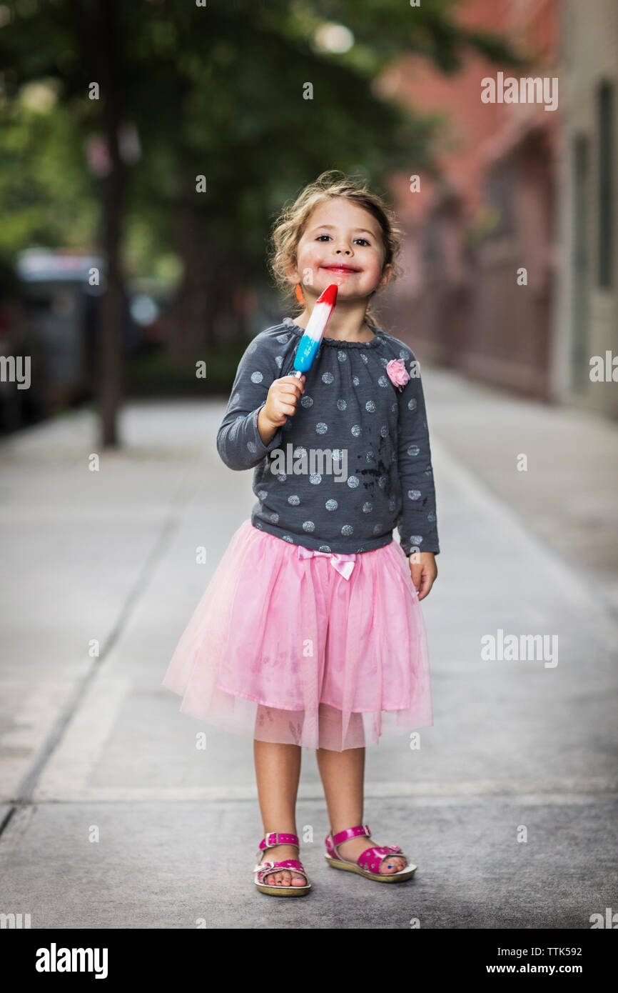 Portrait von cute girl Holding Eis am Stiel auf Fußweg Stockfoto Portrait von cute girl Holding Eis am Stiel auf Fußweg Stockfoto
