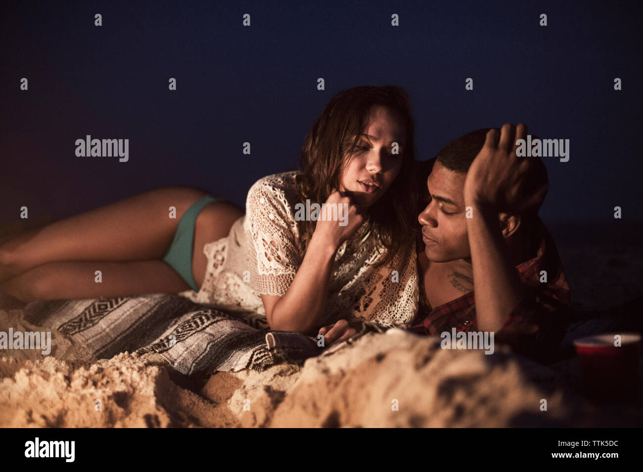 Paar liegen auf Sand am Strand während der Nacht Stockfoto