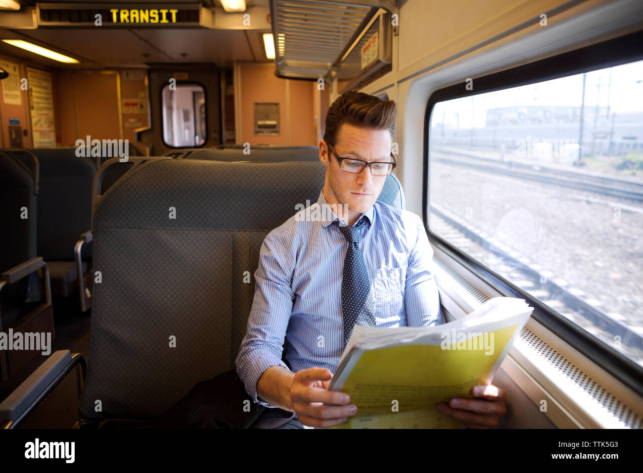 Geschäftsmann, der Zeitung liest, während er im Zug reist Stockfoto
