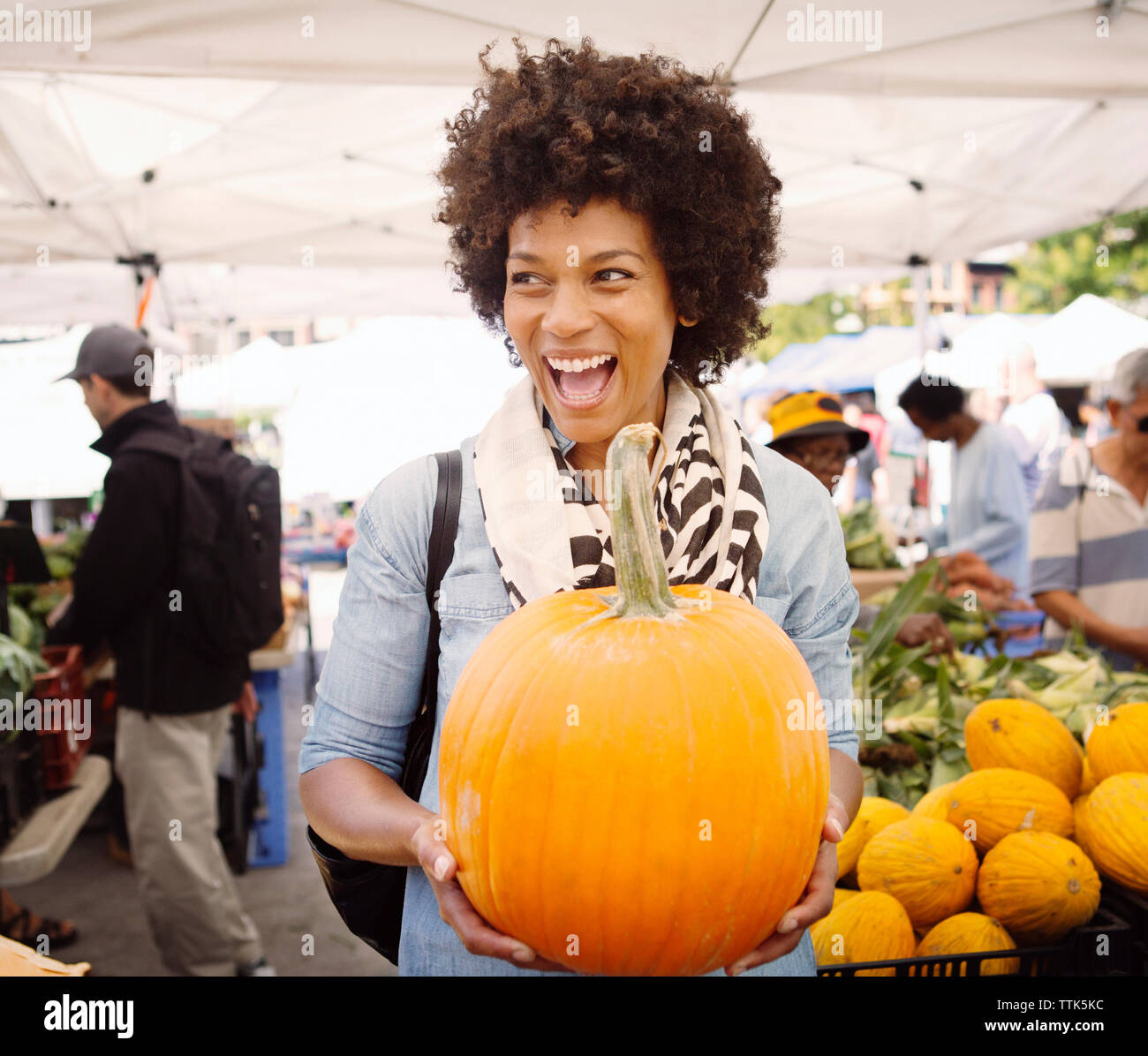 Glückliche Frau mit offenem Mund mit Kürbis am Markt Stockfoto