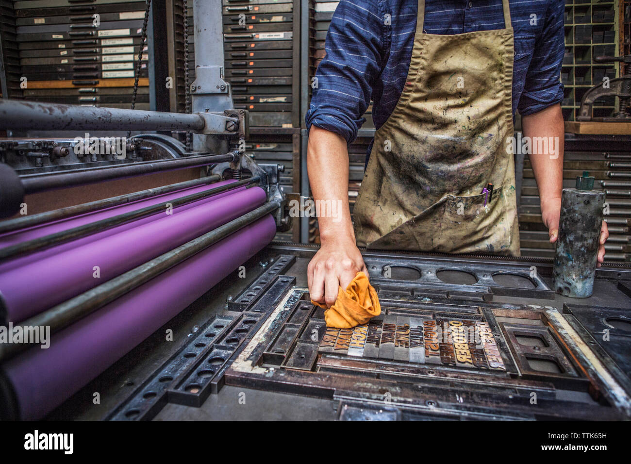Mittelteil des Menschen Reinigung Buchdruck auf Maschinen in der Werkstatt Stockfoto