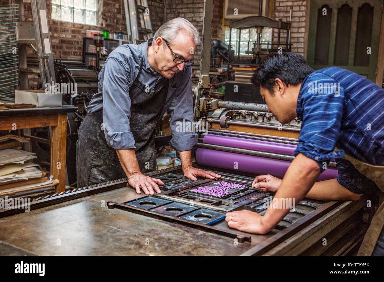 Arbeiter, die in der Werkstatt an Druckmaschinen arbeiten Stockfoto