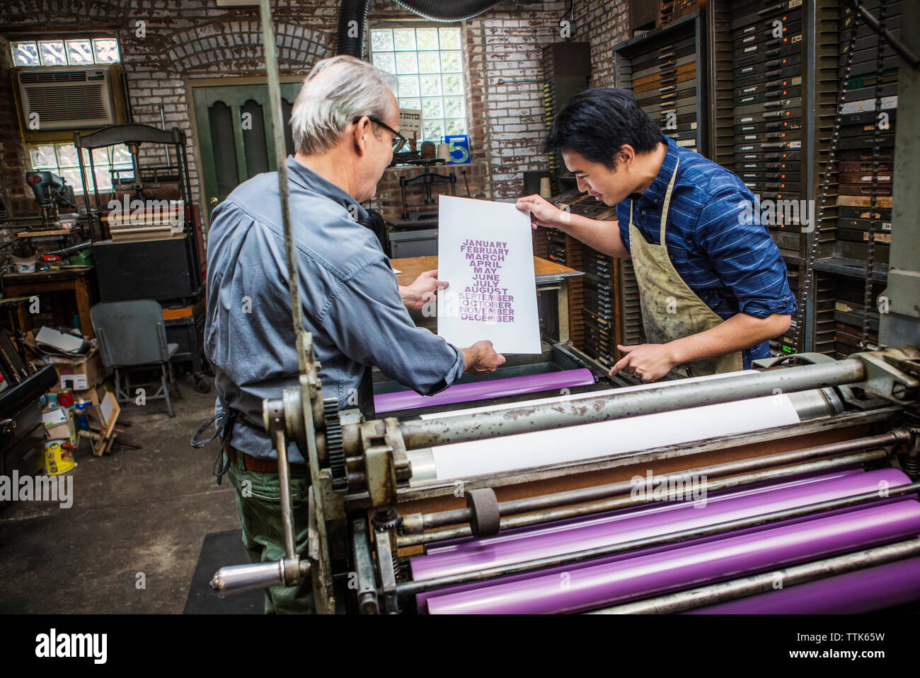Arbeiter, die in der Werkstatt Papier per Buchdruck untersuchen Stockfoto
