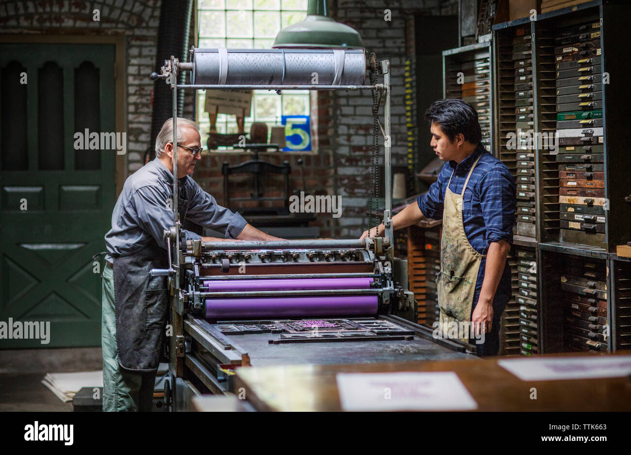 Seitenansicht der Arbeitnehmer stehen durch die Druckmaschine in Werkstatt Stockfoto