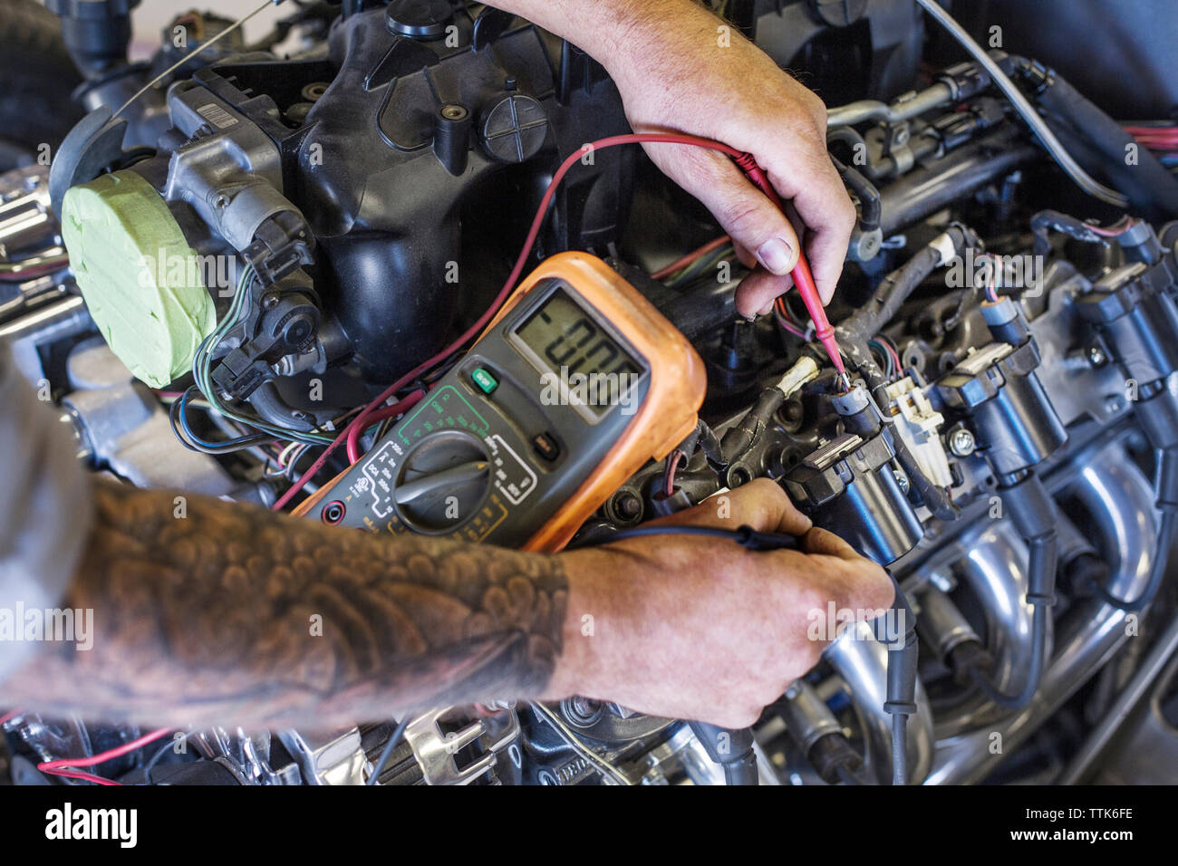 Zugeschnittenes Bild der praktischen Prüfung Auto Motor mit dem Multimeter in der Werkstatt Stockfoto