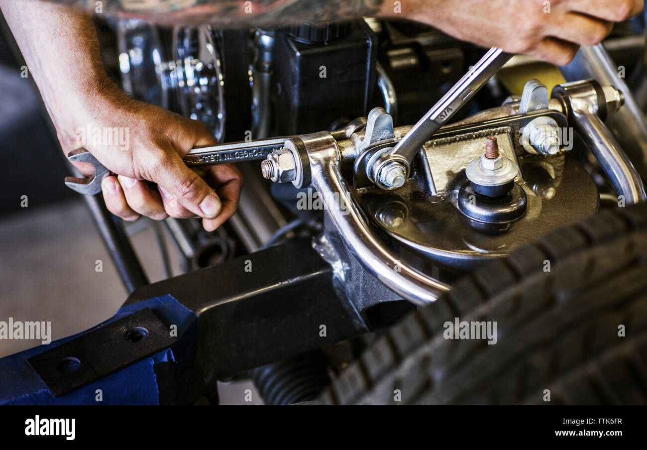 Zugeschnittenes Bild der Hände Befestigungsmuttern von Auto Motor in der Werkstatt Stockfoto