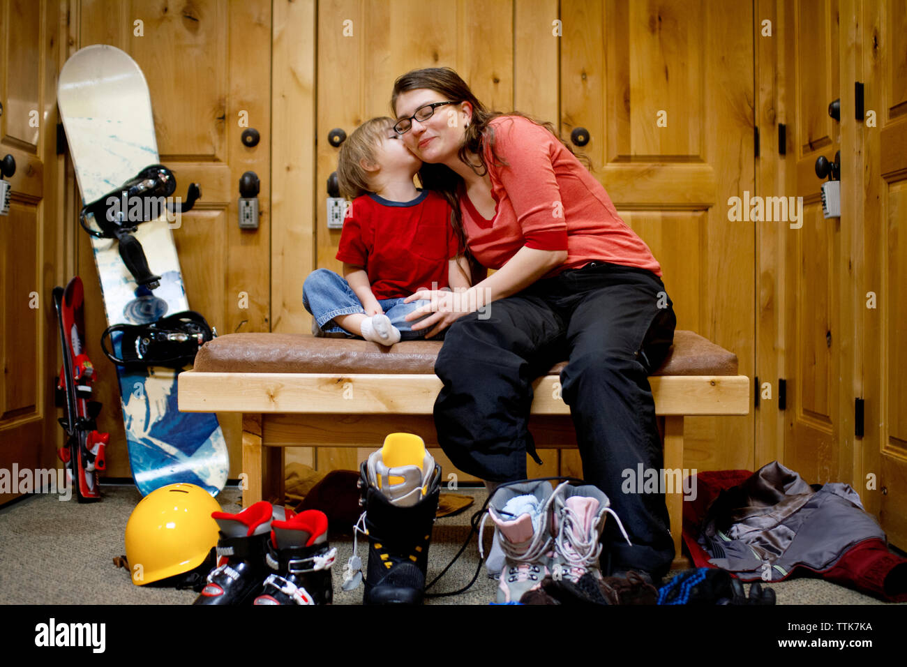 Junge küssen, während Mutter sitzt auf der bank am Ski Resort Stockfoto
