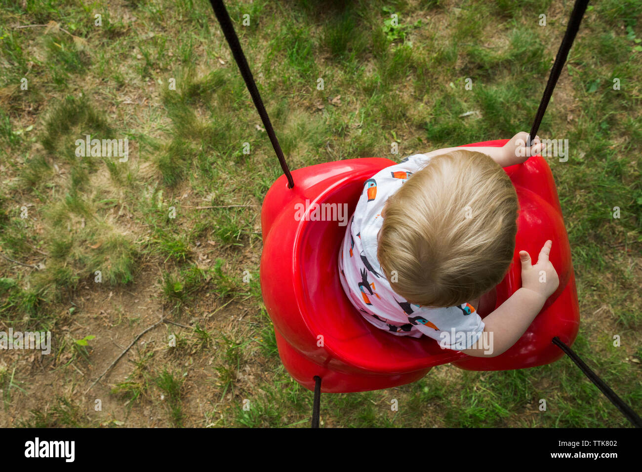 Ansicht von oben von baby boy Schwingen auf rotem Kunststoff Schwingen am Spielplatz Stockfoto