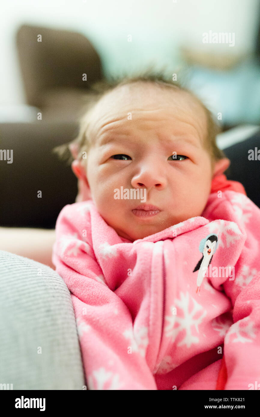 Cute multirassischen Baby Mädchen mit rosa Schneeflocke Schlafanzug gehalten wird Stockfoto