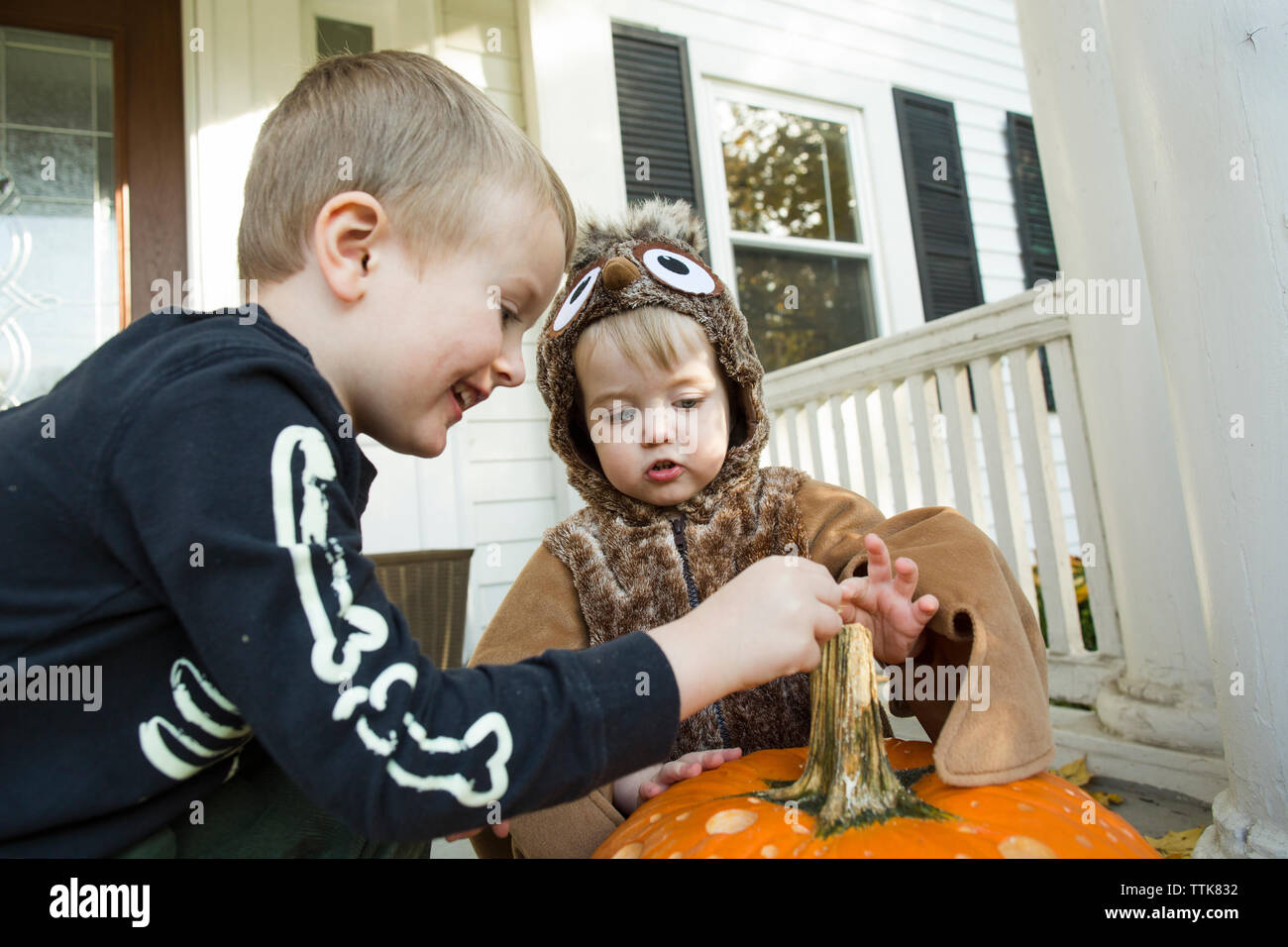 Zwei männliche Kinder für Halloween touch Kürbis auf der Veranda gekleidet Stockfoto
