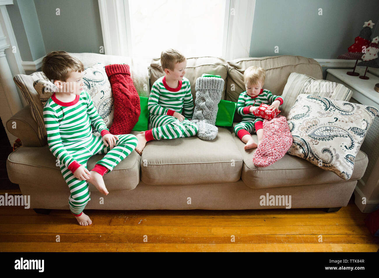Drei Brüder sitzen auf einem Sofa Eröffnung Weihnachten Strümpfe und präsentiert Stockfoto