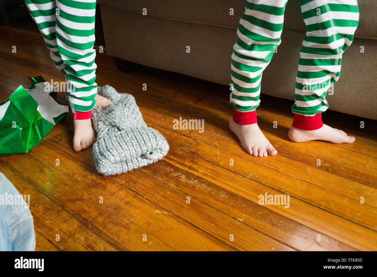 Beine von zwei männlichen Kinder neben Couch am Weihnachtsmorgen Stockfoto