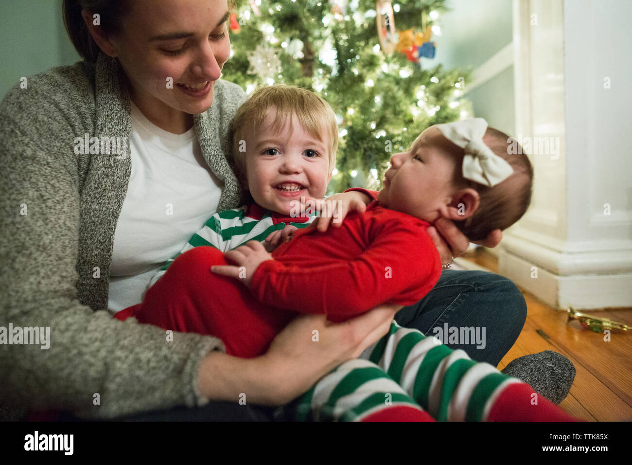 Gerne blonde toddler Boy hält Baby, während bei Kamera schaut lächelnd Stockfoto