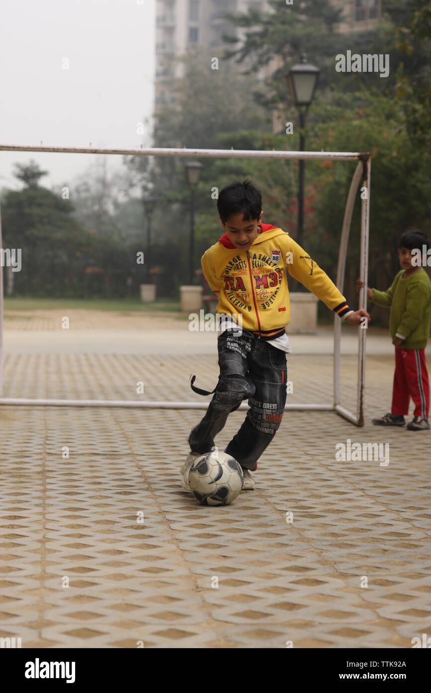 Junge spielt Fußball in einem Hinterhof Stockfoto