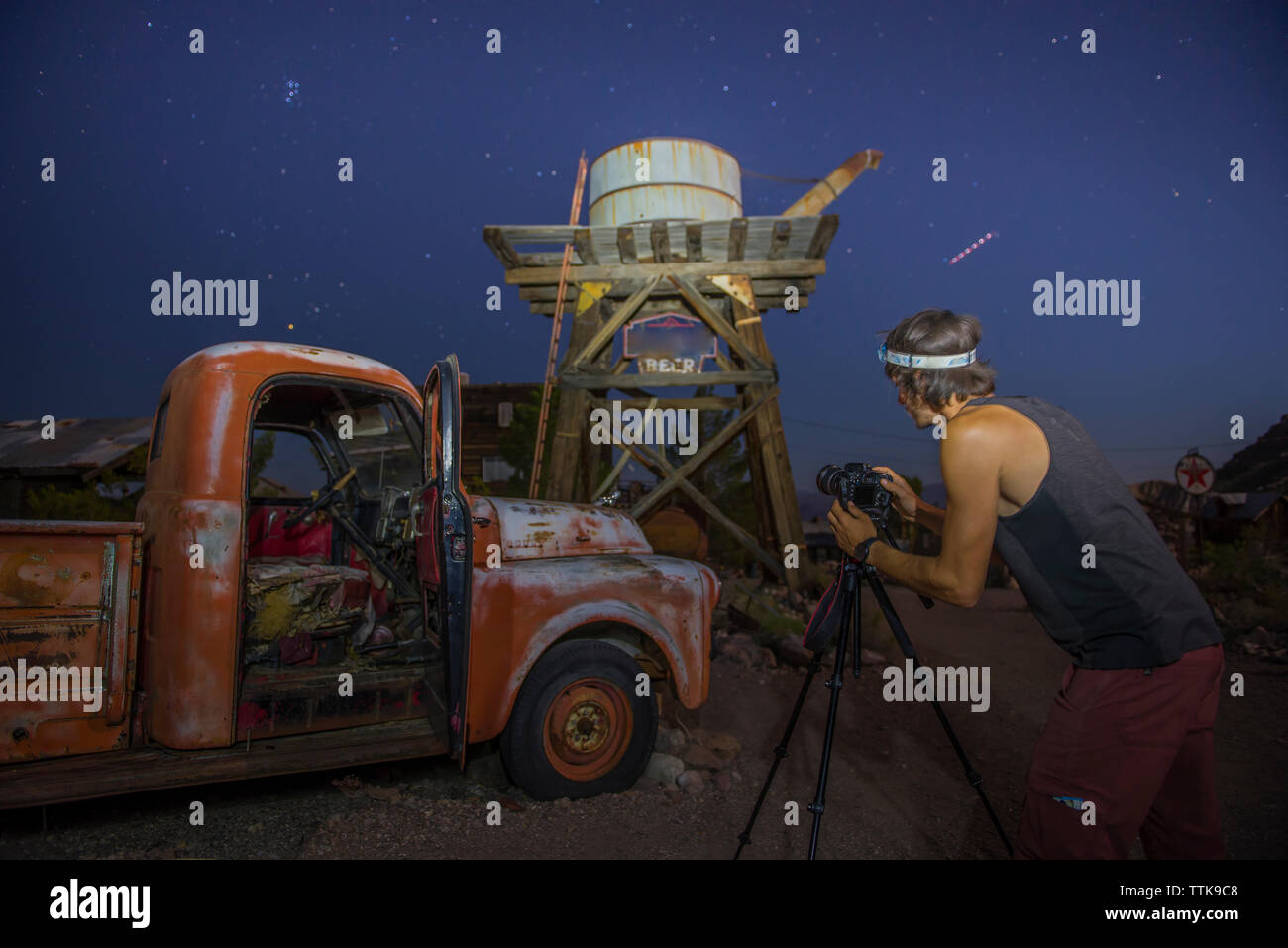 Junge Fotografin Erfassung Oldtimer und Wassertank bei Nacht Stockfoto