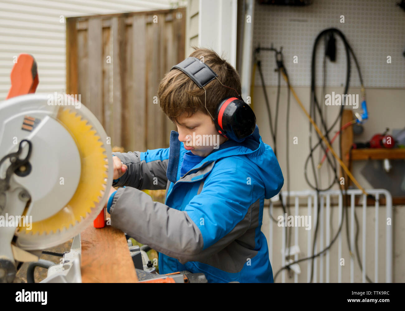 Junge mit Gehörschutz, während im Hinterhof arbeiten Stockfoto