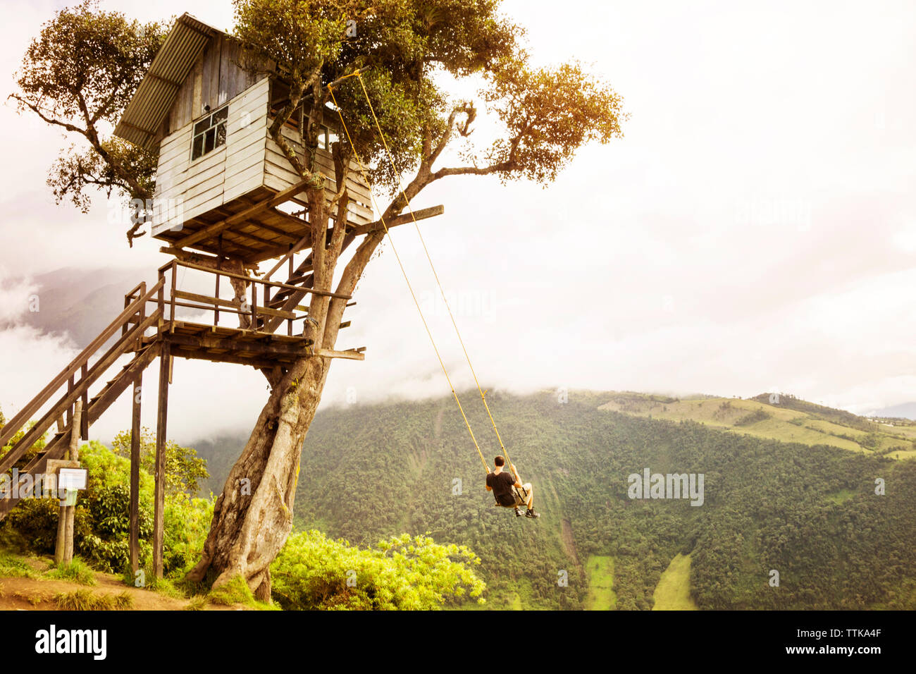 Man genießt auf Swing gegen Berg und Himmel Stockfoto