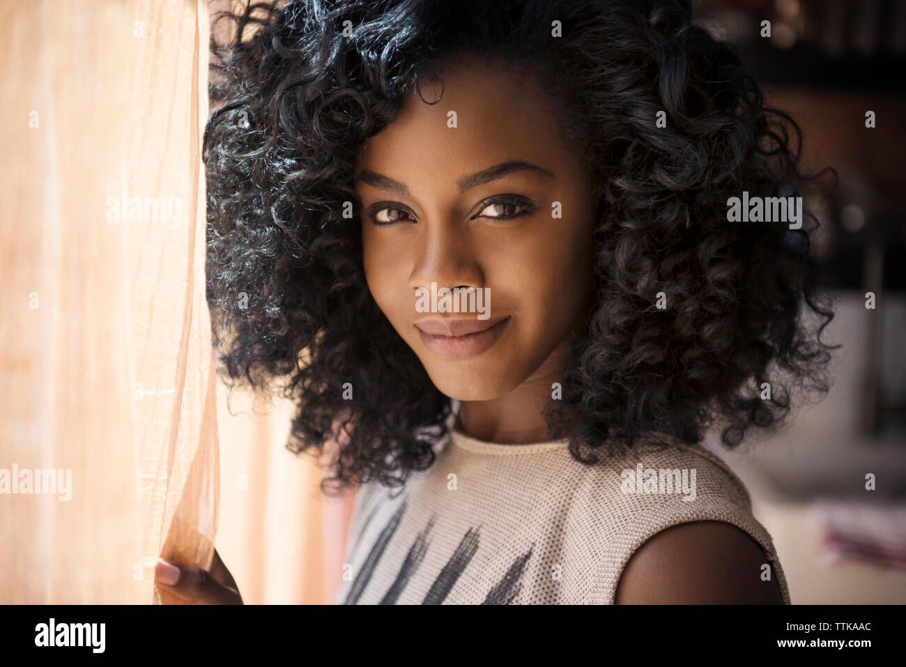 Portrait von lächelnden Frau, durch Vorhang zu Hause Stockfoto