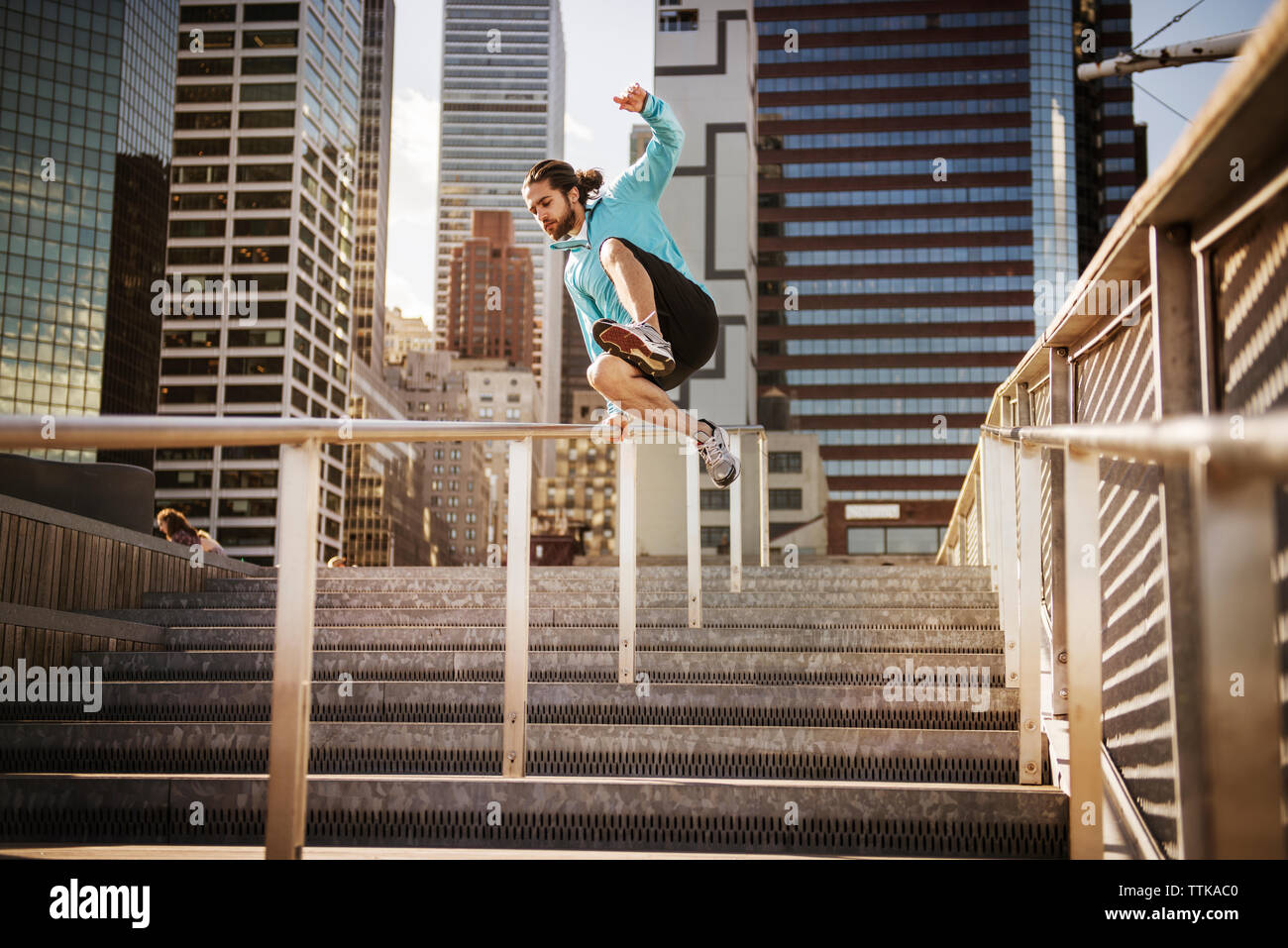 Junger Mann springt auf Treppen gegen Gebäude in der Stadt Stockfoto
