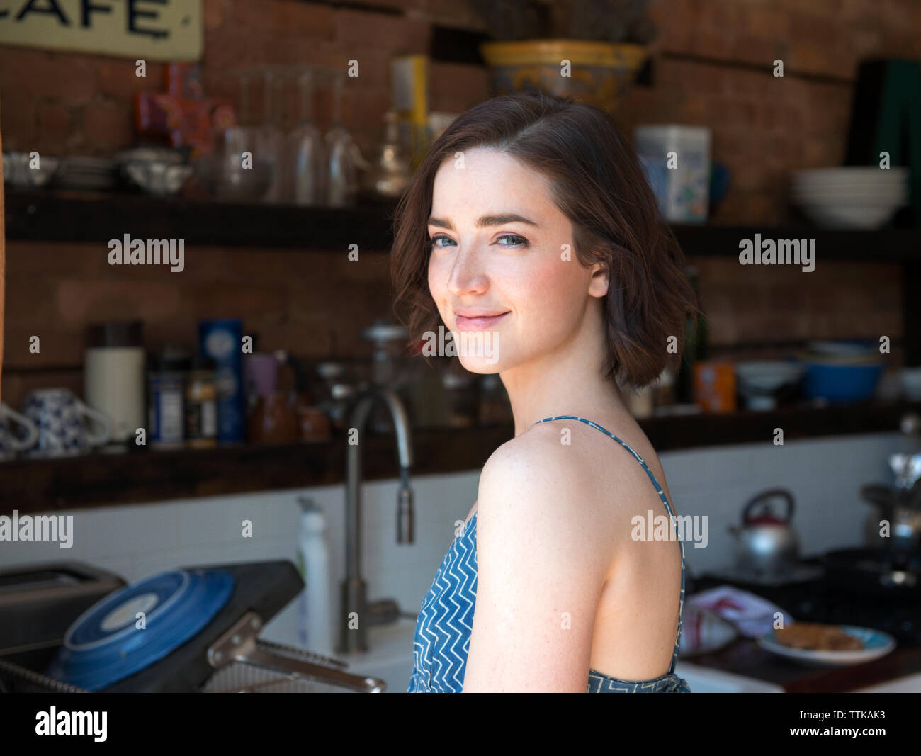 Portrait von lächelnden jungen Frau steht in der Küche Stockfoto