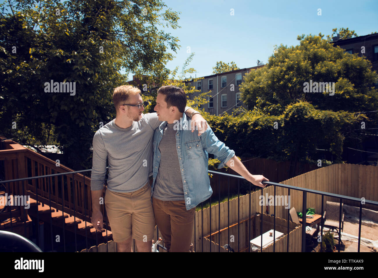 Vorderansicht eines schwulen Paares in Balkon gegen Bäume Stockfoto
