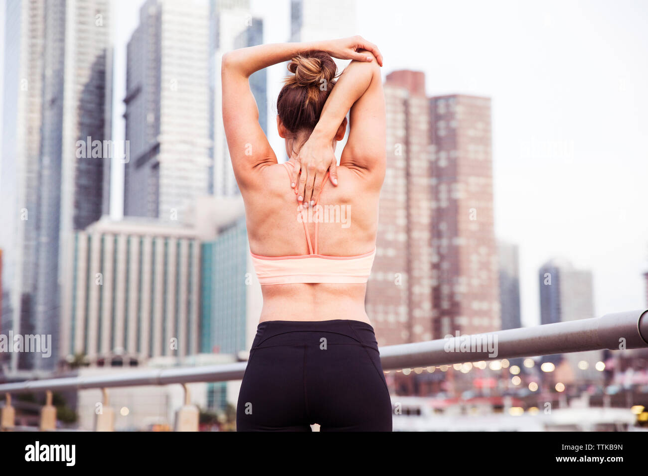 Ansicht der Rückseite Frau stretching Arme hinter Zurück auf der Brücke in der Stadt Stockfoto