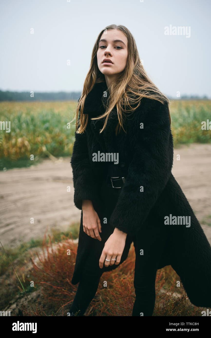 Frau steht in einem Maisfeld bei bewölktem Himmel Stockfoto