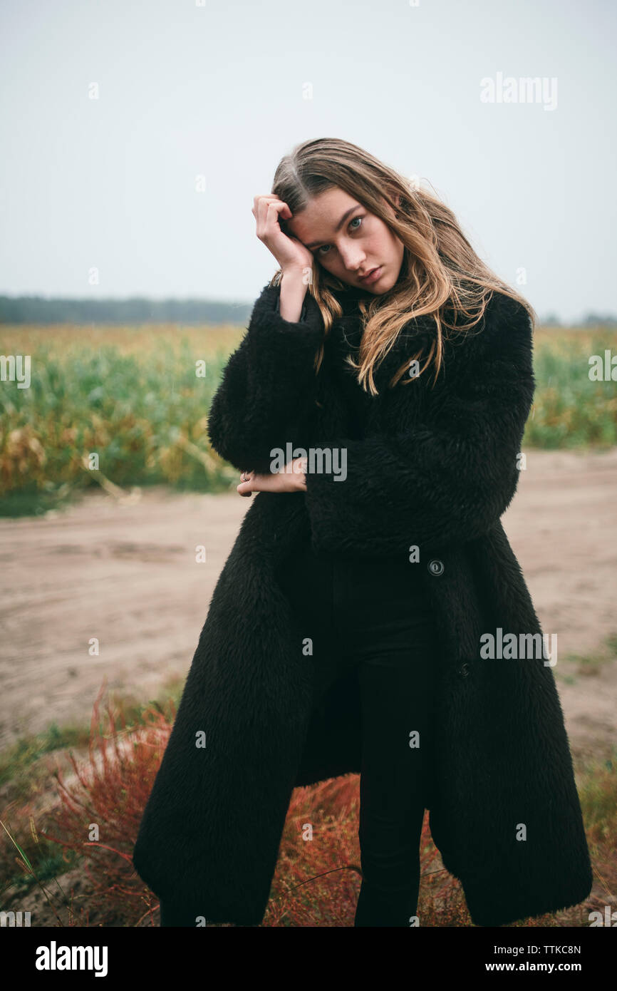 Frau steht in einem Maisfeld bei bewölktem Himmel Stockfoto