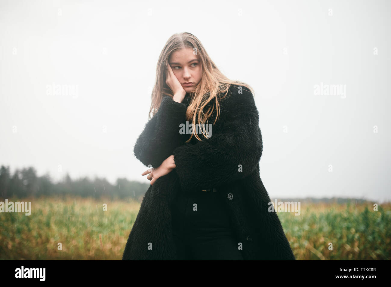 Frau steht in einem Maisfeld bei bewölktem Himmel Stockfoto