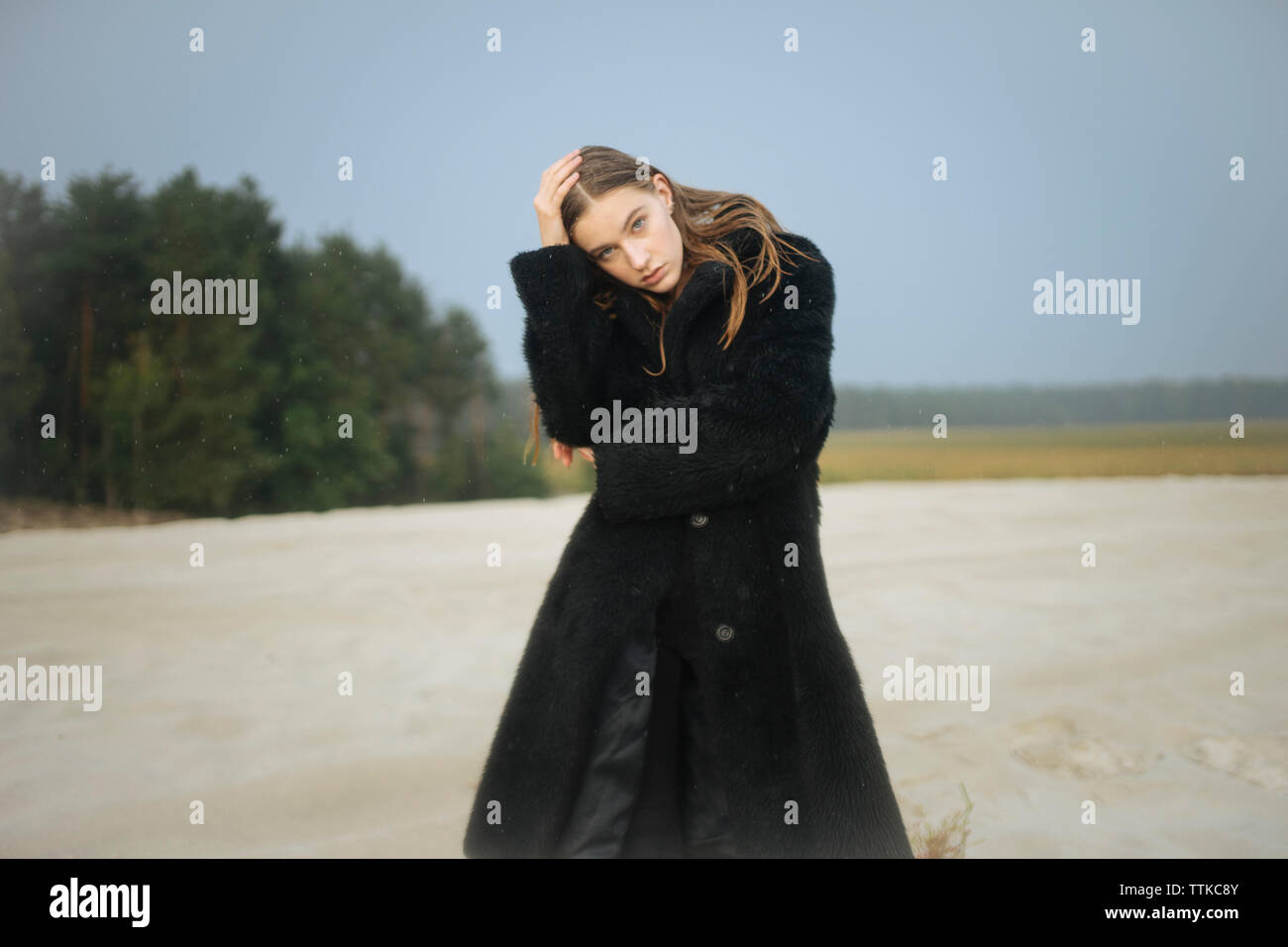 Frau in einem Pelzmantel im Sand in der Regen Stockfoto