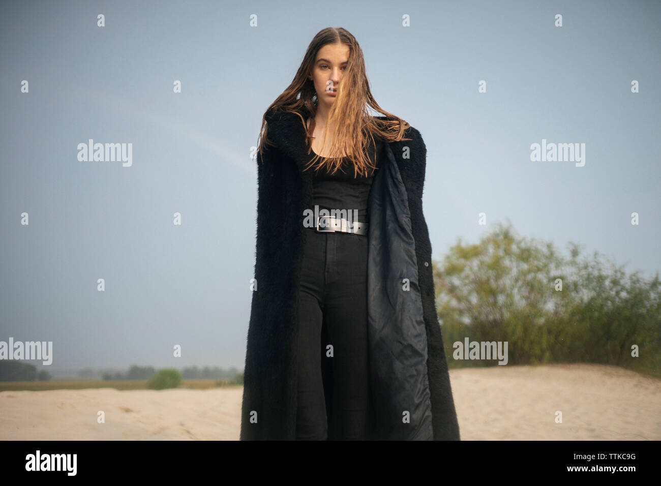 Eine Frau in einem Pelzmantel steht auf dem Sand Stockfoto