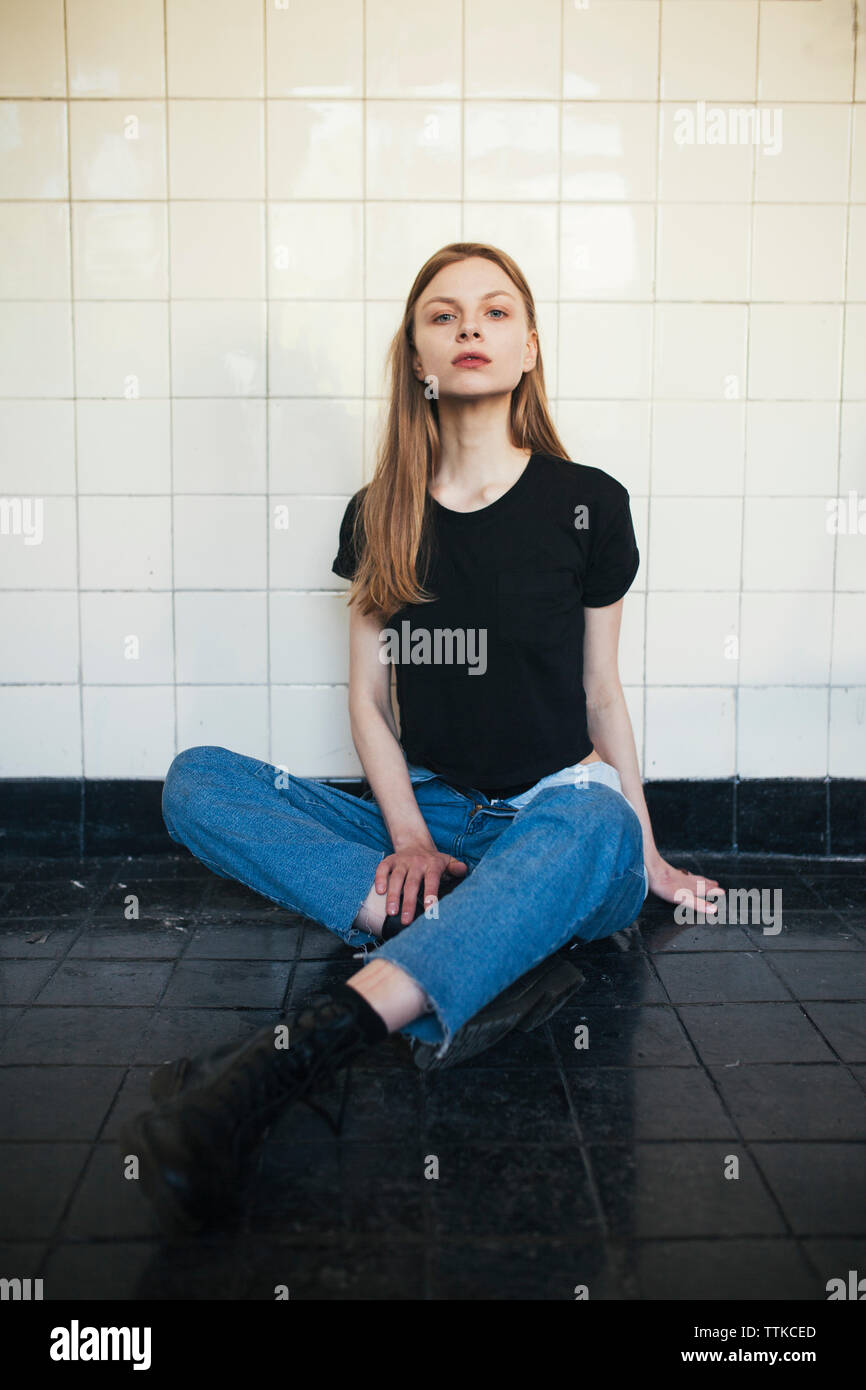 Frau in Fliesen- Zimmer sitzen auf den schwarzen Boden Stockfoto