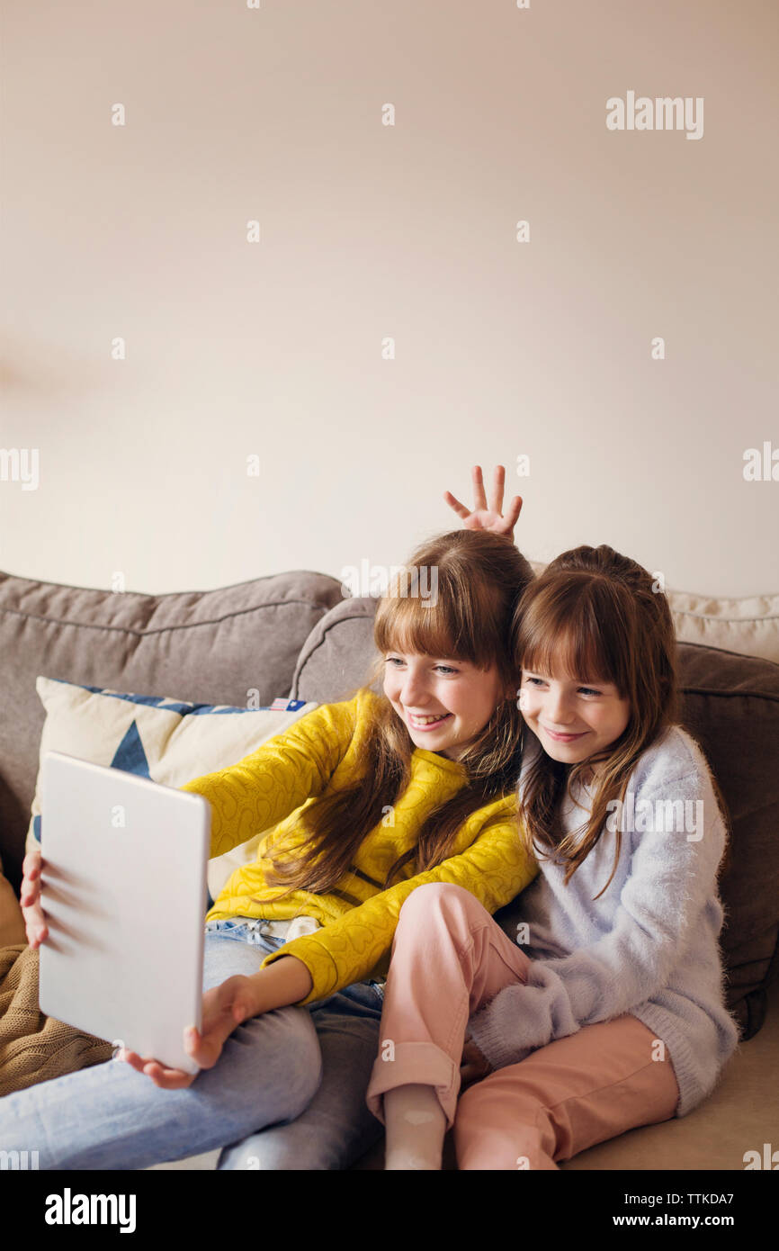 Schwestern unter selfie durch Tablet Computer, während auf dem Sofa zu Hause sitzen Stockfoto