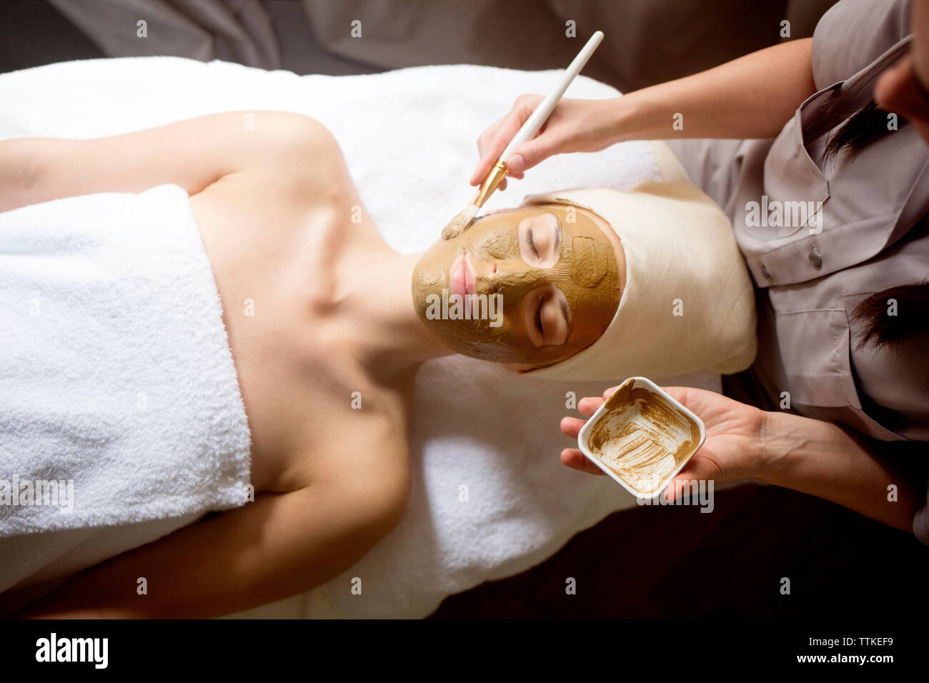 Ansicht der weiblichen Therapeuten Anwendung der Maske auf Gesicht der Frau im Spa Stockfoto