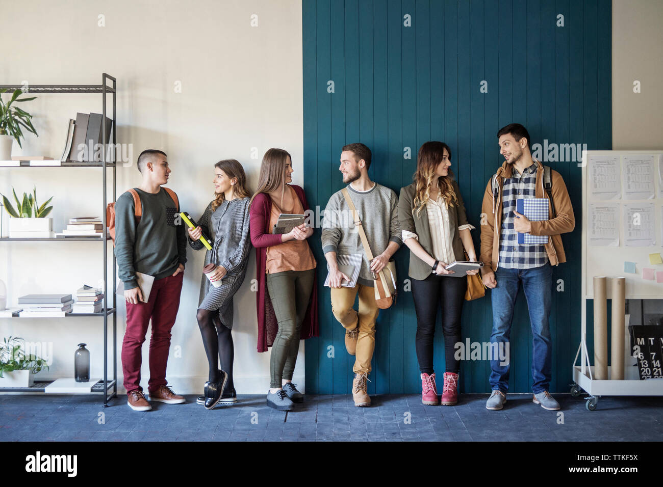 Freunde sprechen, während er gegen die Wand im Klassenzimmer Stockfoto