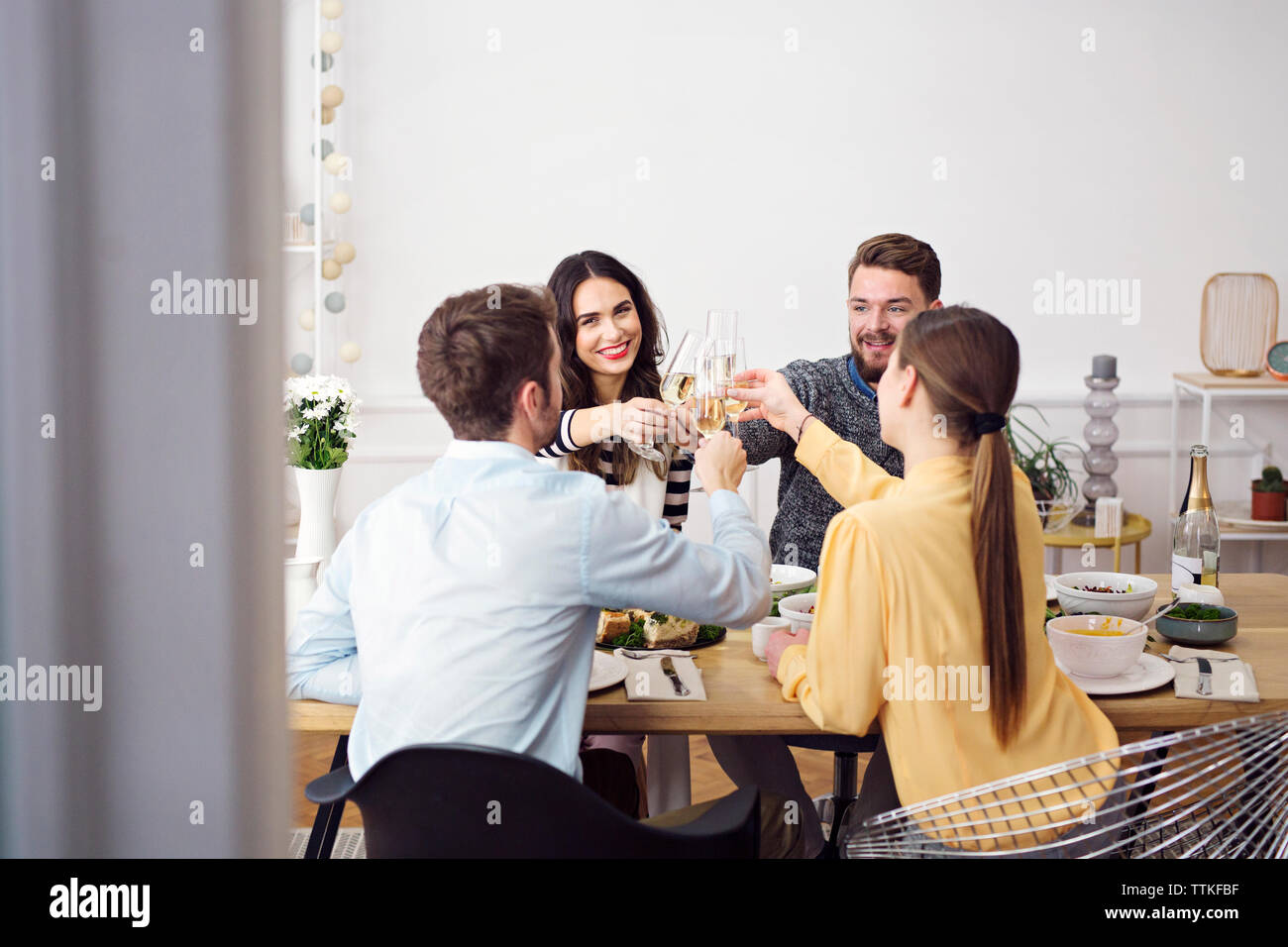 Gerne Freunde toasten Champagnergläser beim Sitzen am Esstisch in Mittagessen Partei Stockfoto
