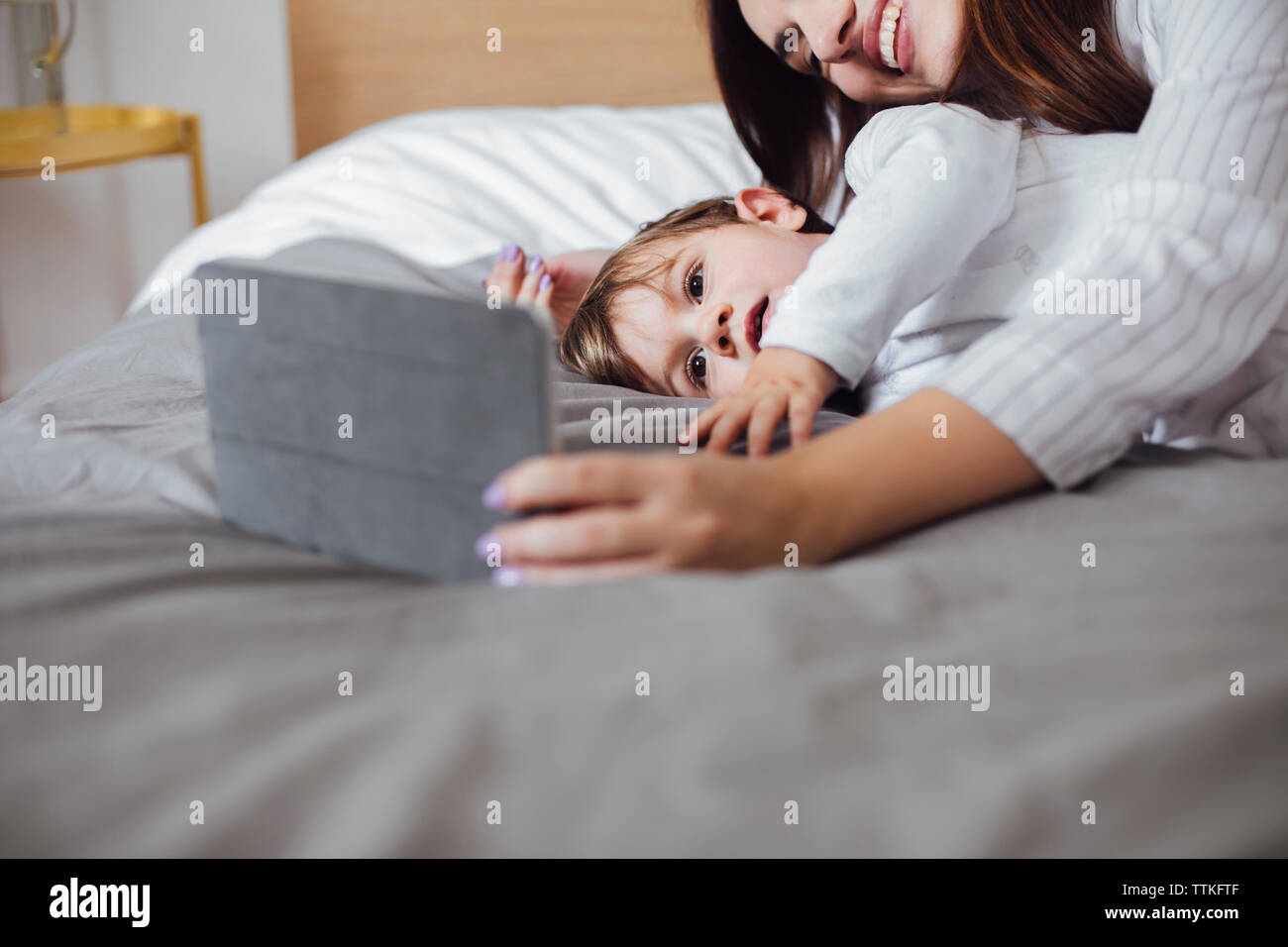 Baby Boy mit Tablet Computer mit Mutter, während im Bett lag, Stockfoto