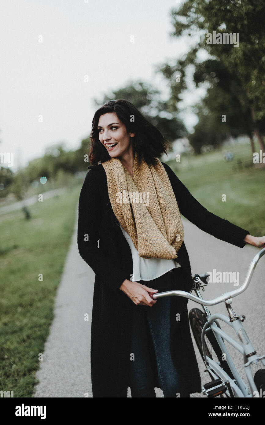 Fröhliche Frau mit Fahrrad Wandern im Park Stockfoto