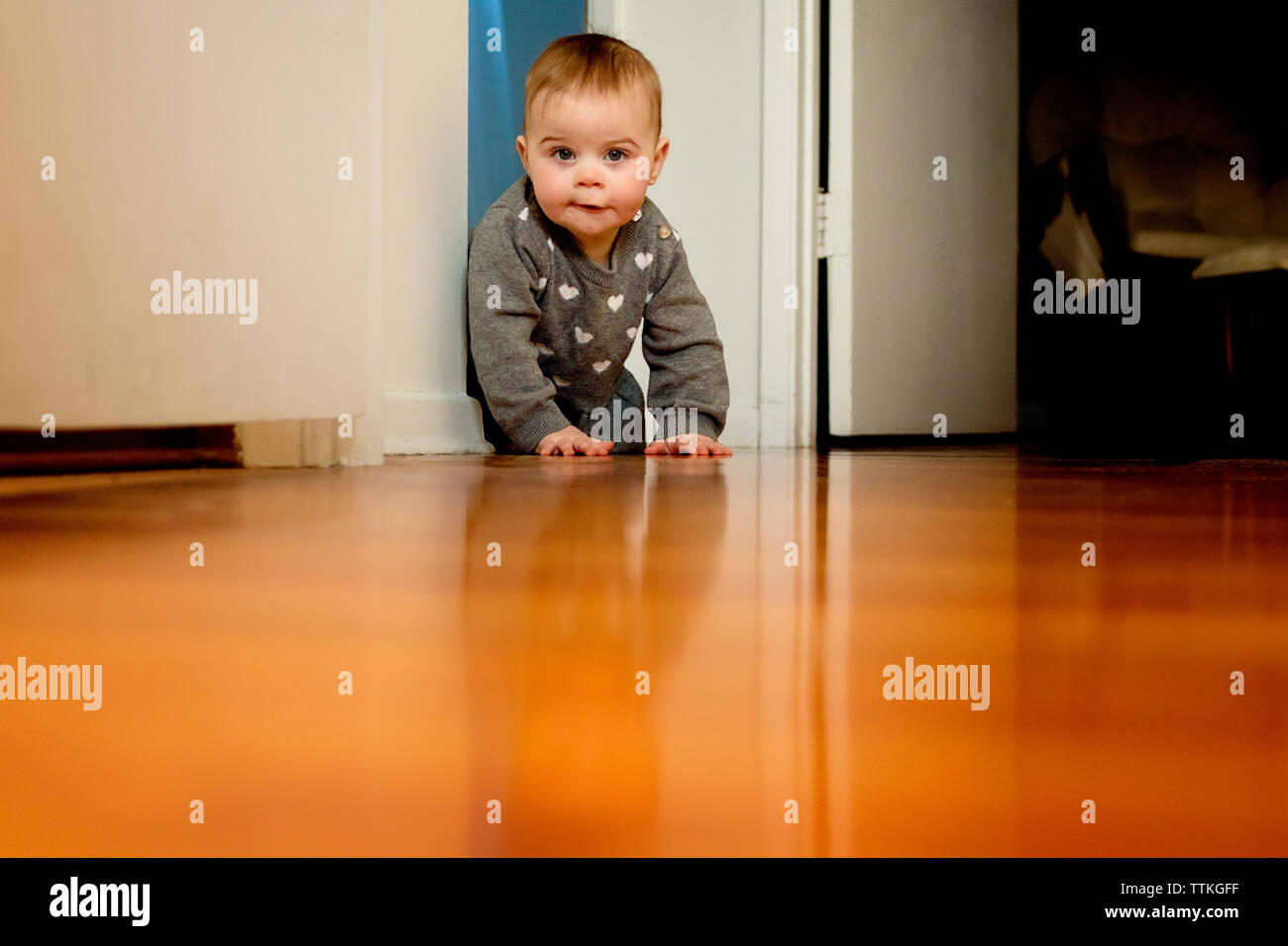 Ein Baby krabbeln auf dem Boden hinter der Tür weg Stockfoto
