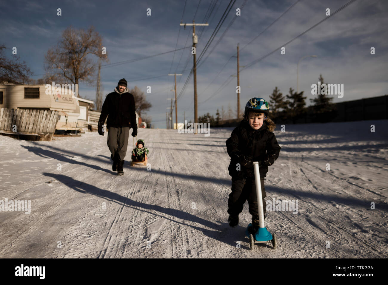 Junge reiten Roller, Gasse mit seiner Familie im Winter Stockfoto