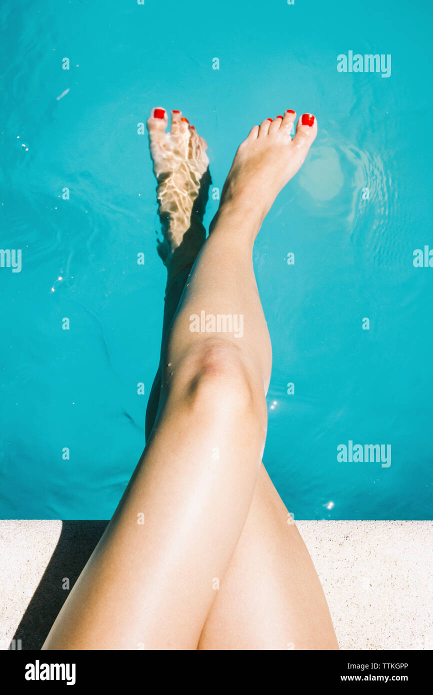 First Person Ansicht der Beine und Füße der Frau am Pool Stockfoto
