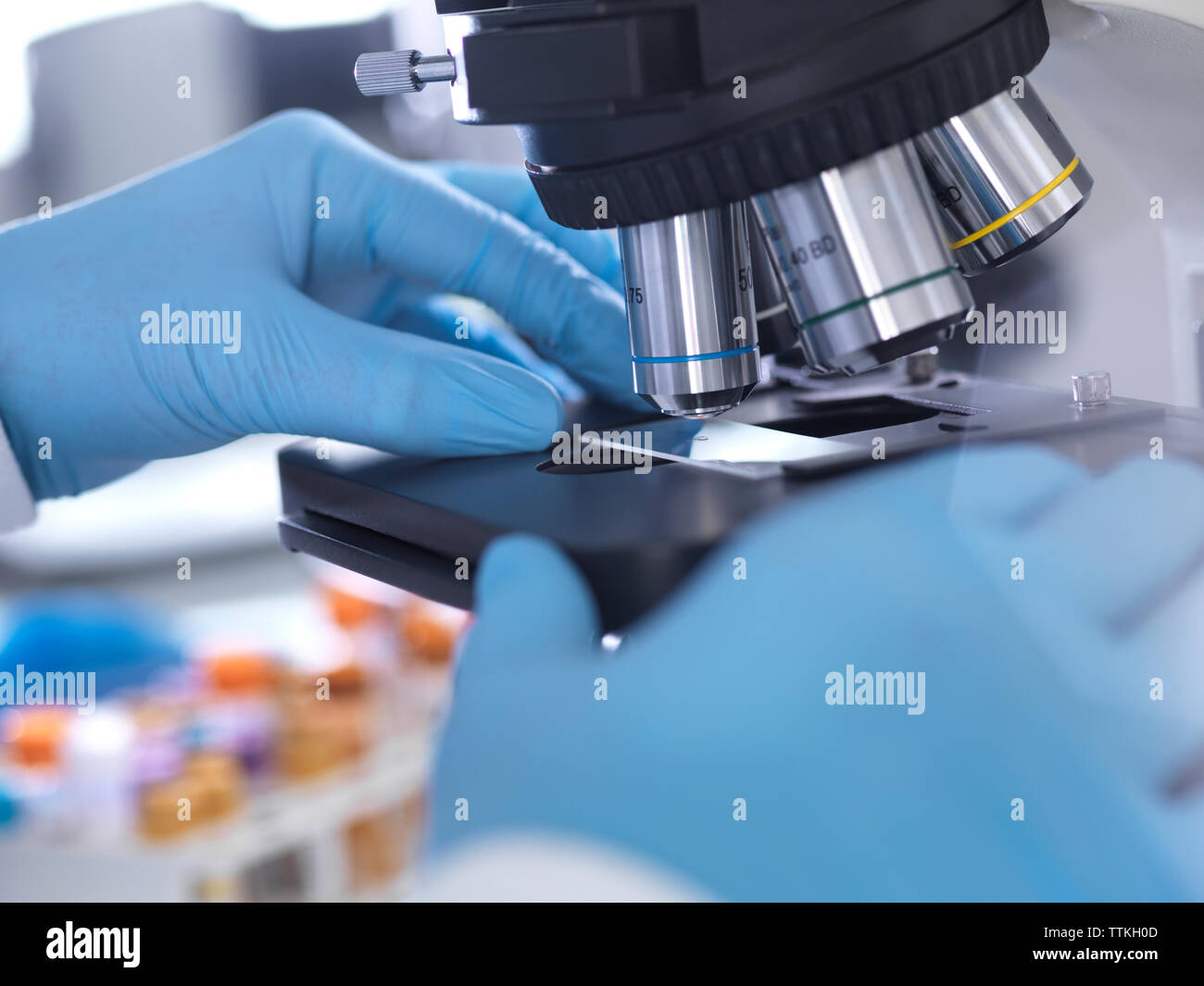 7/8 Händen der männlichen Wissenschaftler analysieren Blutprobe durch Mikroskop im Labor Stockfoto