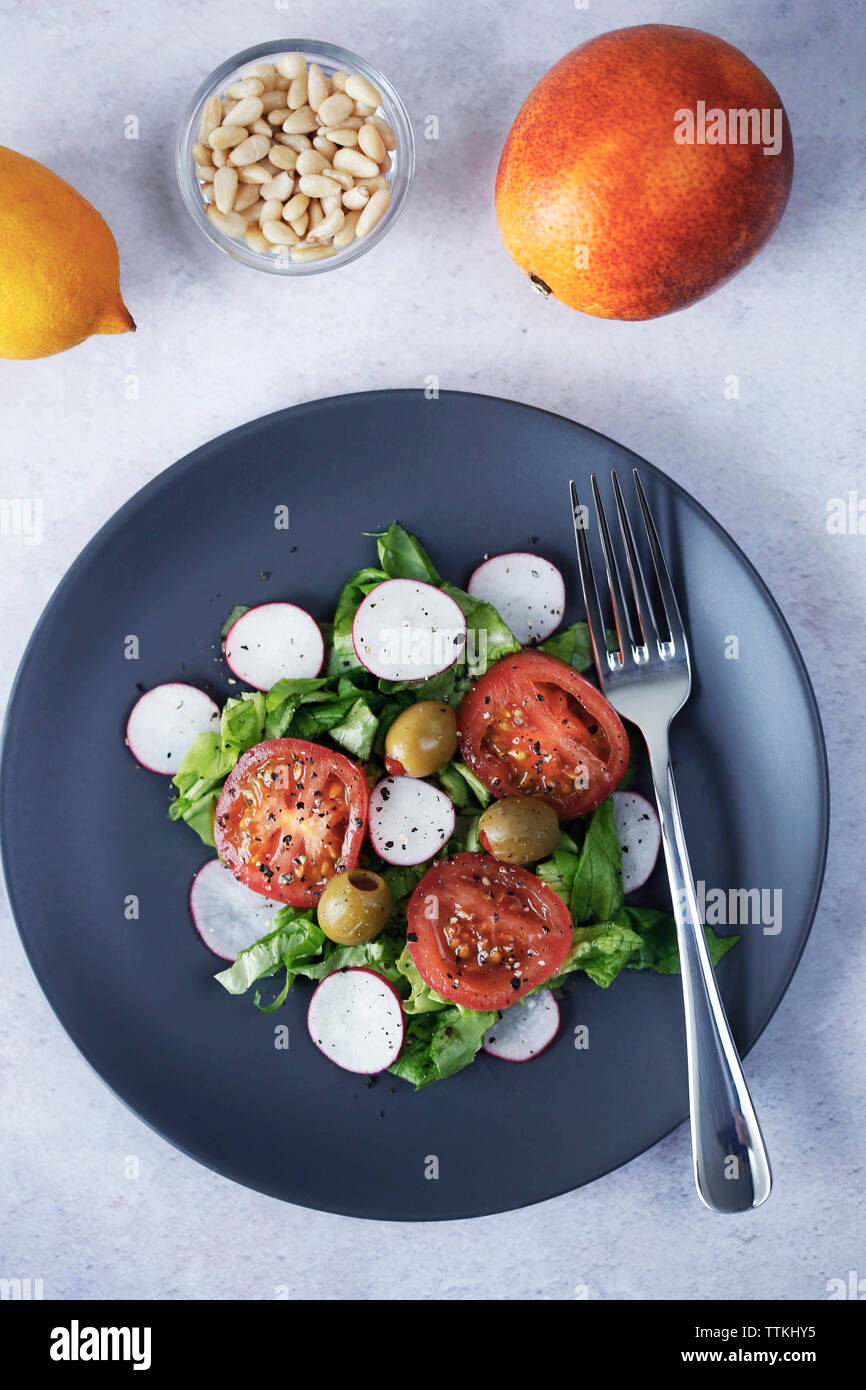 Ansicht von oben der Salat in der Platte mit Zitrusfrüchten serviert und Pinienkerne auf Tisch Stockfoto